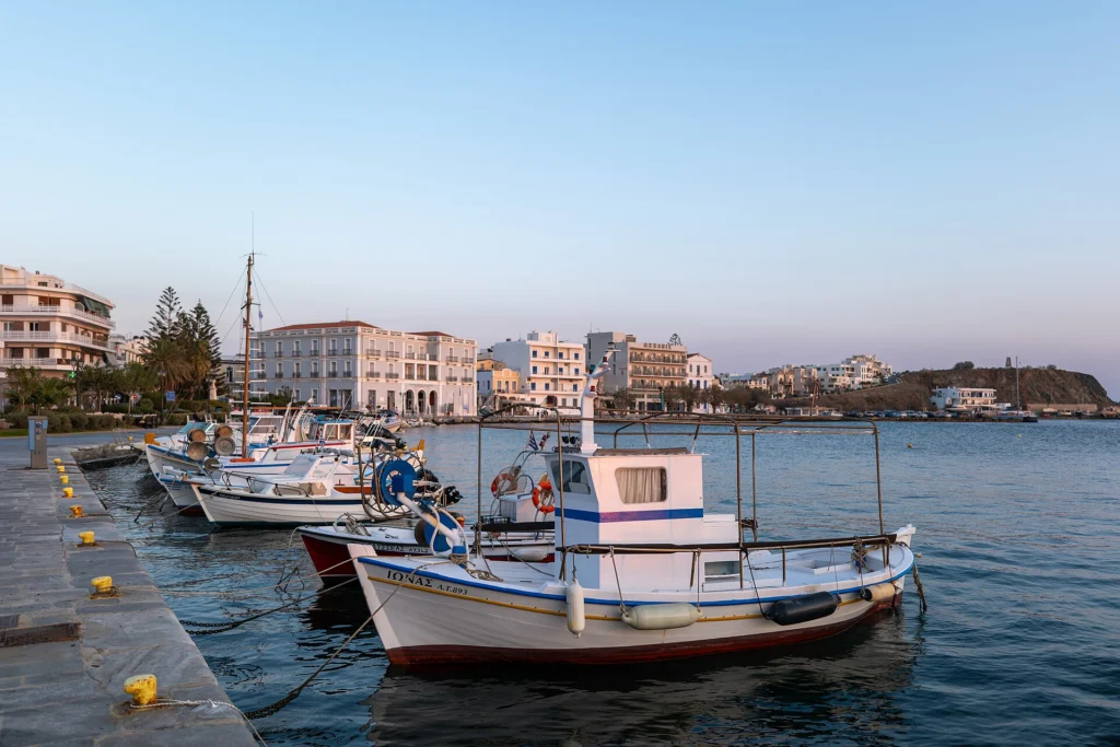 Αλιευτικά καΐκια δεμένα στην προκυμαία του λιμανιού της Τήνου με κτίρια της πόλης στο βάθος