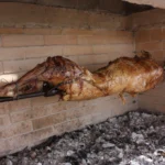 Ολόκληρο αρνί ψήνεται σε σούβλα πάνω από αναμμένα κάρβουνα σε πέτρινη ψησταριά
