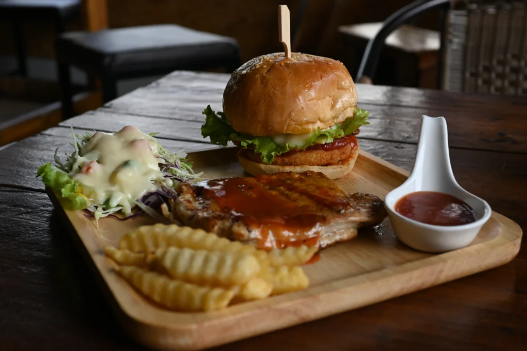 Burger με πατάτες τηγανητές, σαλάτα λάχανο και σάλτσα σε ξύλινο δίσκο σερβιρίσματος
