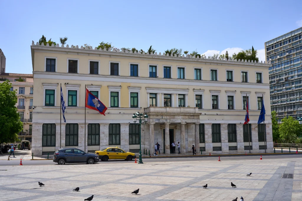Το νεοκλασικό Δημαρχείο της Αθήνας στην οδό Αθηνάς με σημαίες, όπως φαίνεται από την πλατεία Κοτζιά