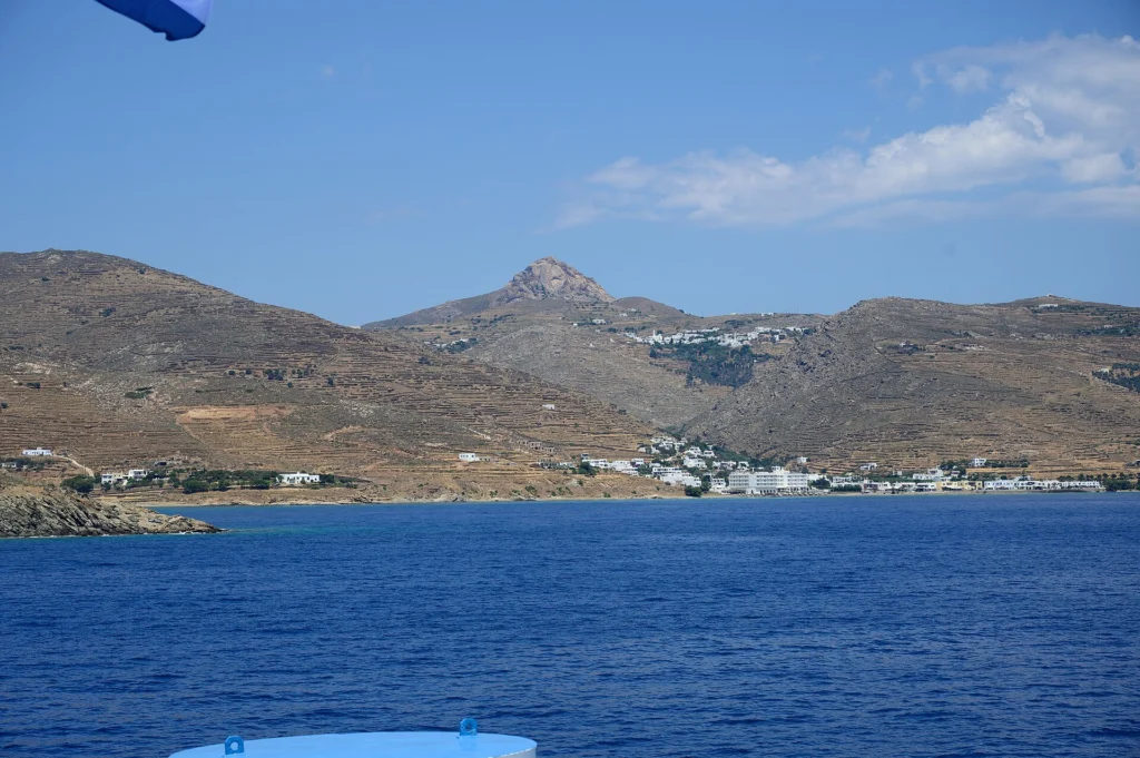 Το βραχώδες Εξώμβουργο πάνω από πεζούλες και λευκούς οικισμούς της Τήνου, όπως φαίνεται από το πλοίο