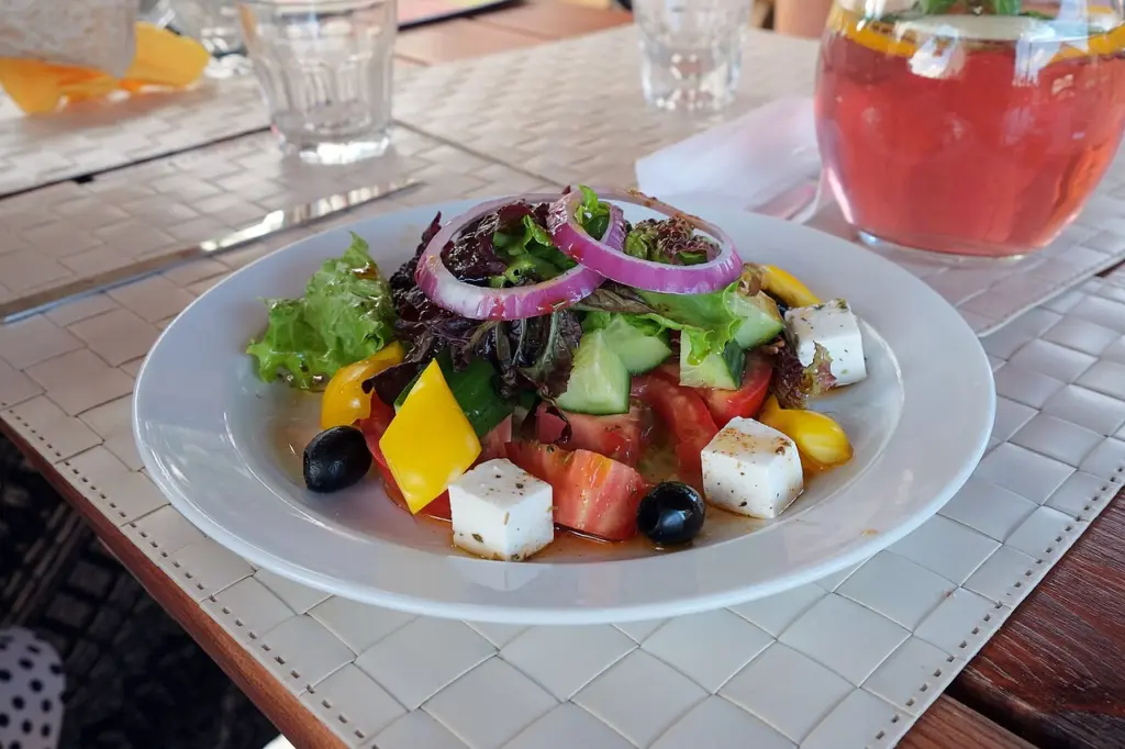 Πιάτο με σαλάτα «Greek salad» που έχει φύλλα μαρουλιού, ντομάτα, αγγούρι, κρεμμύδι, ελιές και κύβους λευκού τυριού
