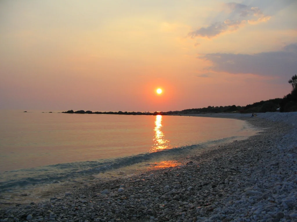 Ηλιοβασίλεμα πάνω από τη θάλασσα με βοτσαλωτή παραλία κοντά στην Καλαμάτα και φως στο νερό
