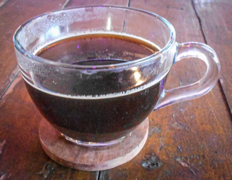 Γυάλινο φλιτζάνι με καφέ αμερικάνο, σκούρο ρόφημα με λεπτή κρέμα, πάνω σε ξύλινο τραπέζι