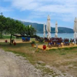 Ξύλινα τραπέζια και καρέκλες ταβέρνας δίπλα στη θάλασσα με κλειστές ομπρέλες στη Θάσο, καλοκαιρινή μέρα