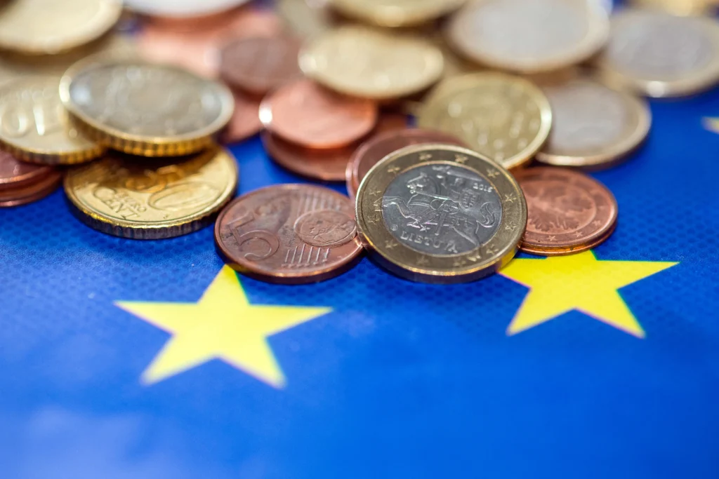 Κέρματα ευρώ πάνω σε μπλε σημαία της Ευρωπαϊκής Ένωσης με κίτρινα αστέρια