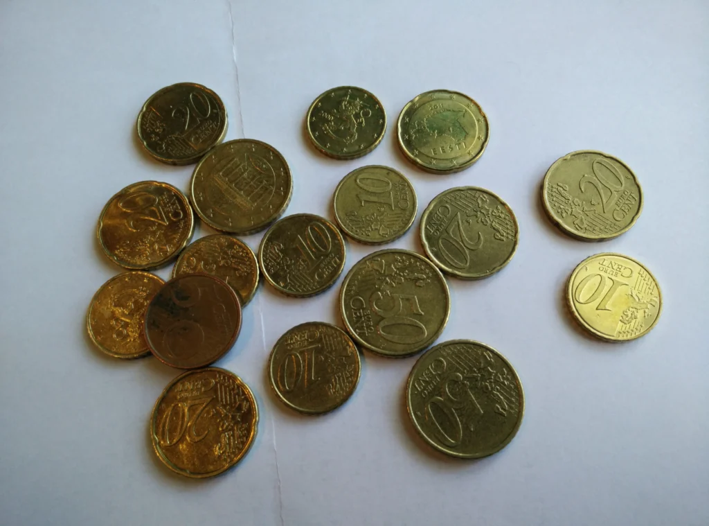 Χρυσά κέρματα ευρώ των 10, 20 και 50 λεπτών σκορπισμένα πάνω σε λευκή επιφάνεια