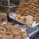 Πάγκος στην Αθήνα με στοίβες από κουλούρια με σουσάμι και στρογγυλά αρτοσκευάσματα με γλάσο ζάχαρης