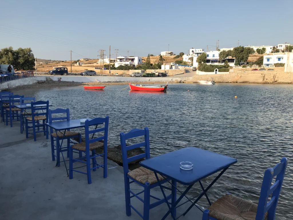 Άδεια τραπέζια ταβέρνας με μπλε καρέκλες δίπλα στη θάλασσα στο Πάνω Κουφονήσι, πριν έρθουν οι πελάτες