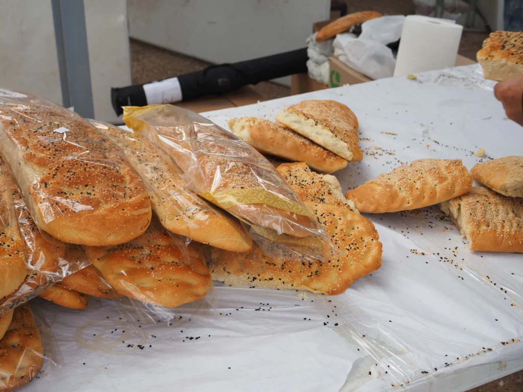Λαγάνες με σουσάμι, ολόκληρες και σε κομμάτια, σε σακούλες πάνω σε τραπέζι με λευκό τραπεζομάντιλο