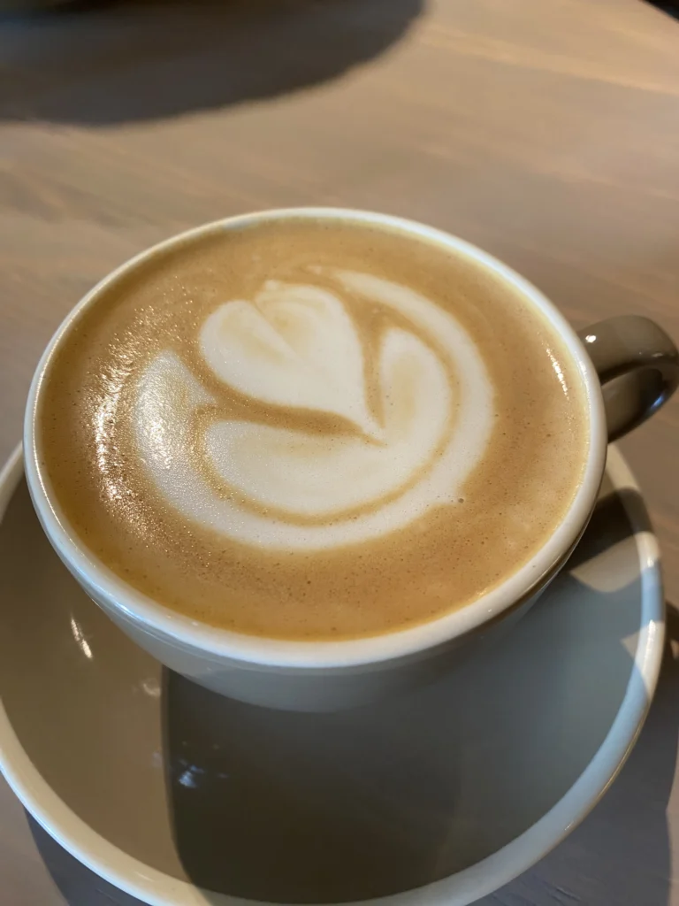 Ζεστό λάτε με φυτικό ρόφημα και σχέδιο latte art σε γκρι φλιτζάνι πάνω σε ξύλινο τραπέζι