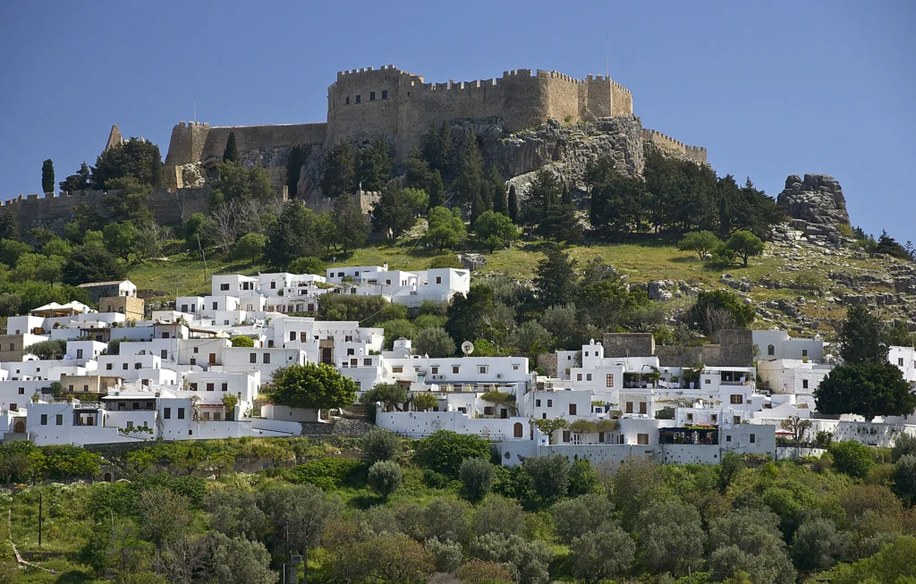 Φωτογραφία της Λίνδου στη Ρόδο: λευκά σπίτια κάτω από το κάστρο της ακρόπολης και ελαιόδεντρα
