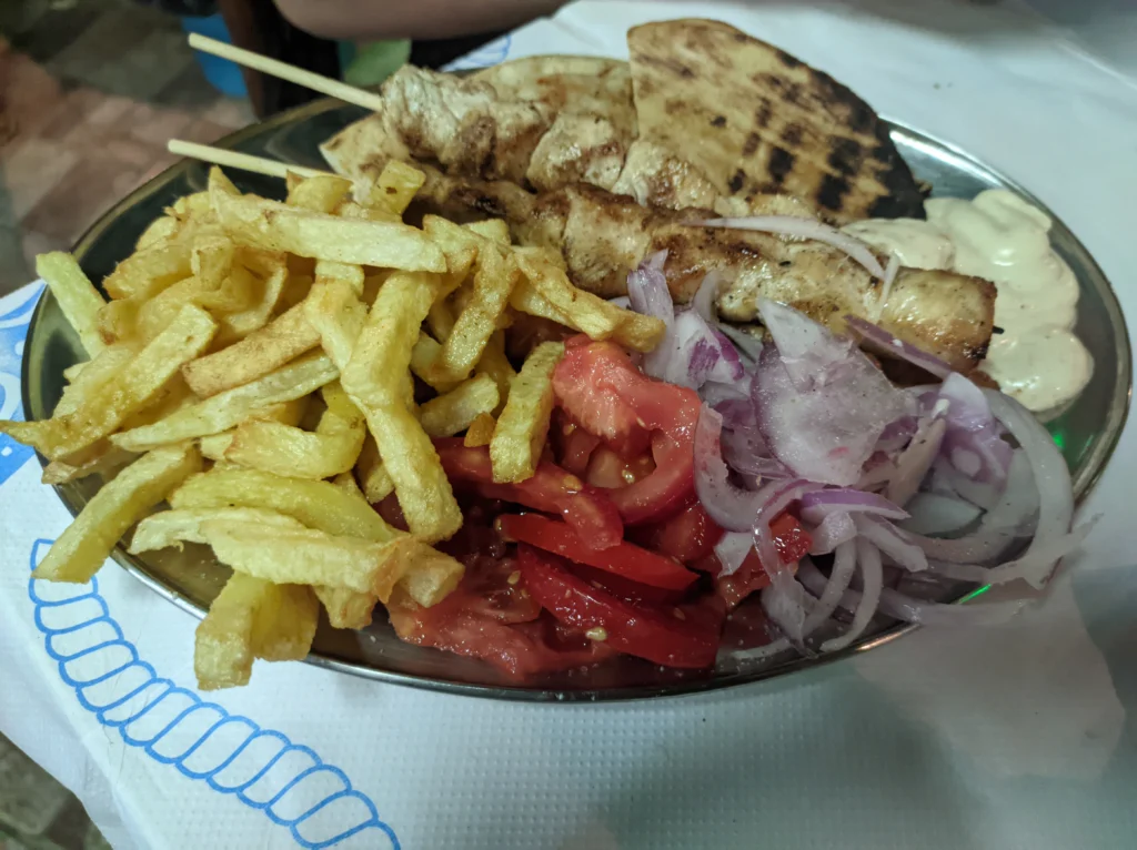 Μεταλλικό πιάτο με καλαμάκια κοτόπουλο, τηγανητές πατάτες, ντομάτα, κόκκινο κρεμμύδι, πίτα και σως