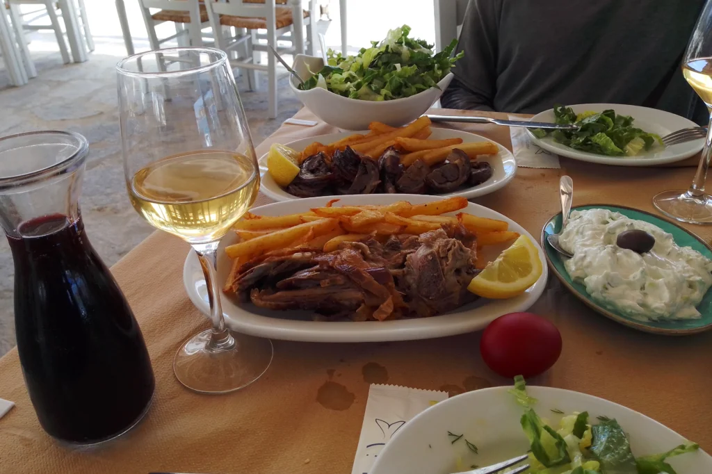 Τραπέζι ταβέρνας με αρνί σούβλας, κοκορέτσι, τζατζίκι, σαλάτα, κόκκινο αυγό και κρασί