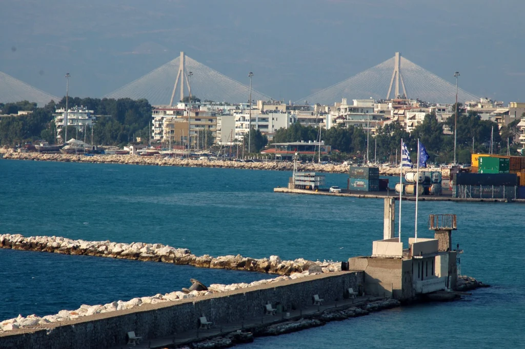 Φωτογραφία του λιμανιού της Πάτρας με πολυκατοικίες της παραλίας και τη γέφυρα Ρίου-Αντιρρίου στο βάθος
