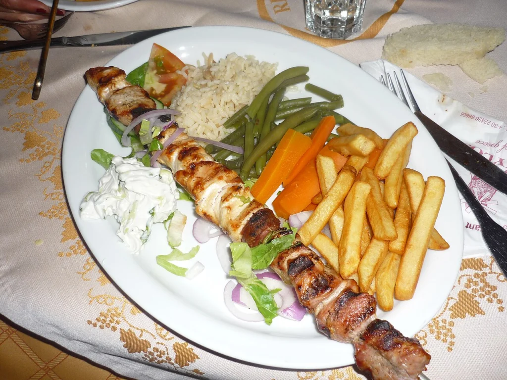 Πιάτο με σουβλάκι, ρύζι, φασολάκια, καρότο, τζατζίκι και τηγανητές πατάτες σε τραπεζομάντιλο