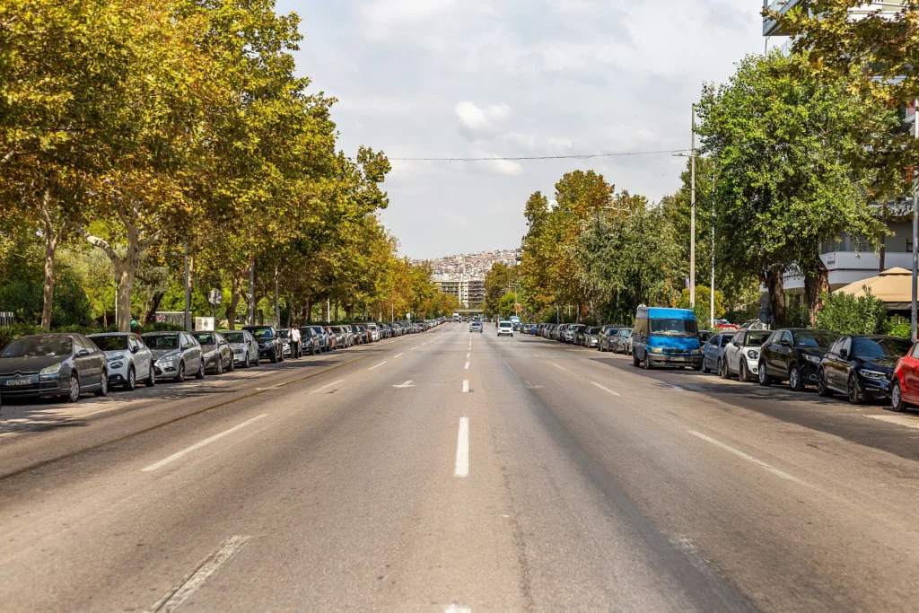 Η Λεωφόρος Μεγάλου Αλεξάνδρου στη Θεσσαλονίκη με δέντρα και σταθμευμένα αυτοκίνητα, διαδρομή της παρέλασης