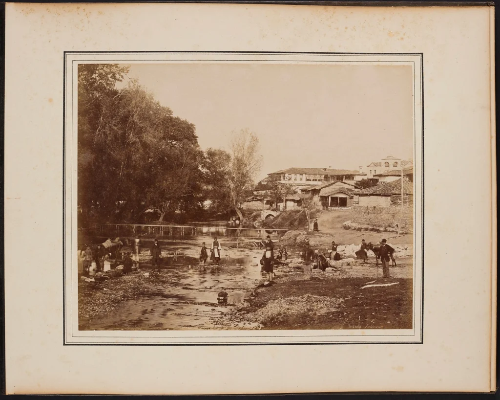 Παλιά φωτογραφία του 1885 με την είσοδο της πόλης των Τρικάλων, χαμηλά σπίτια και το κάστρο στο βάθος του λόφου