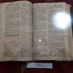 Ανοιχτό παλιό έντυπο βιβλίο Τριωδίου του 1747 με κόκκινα και μαύρα γράμματα, σε προθήκη μουσείου