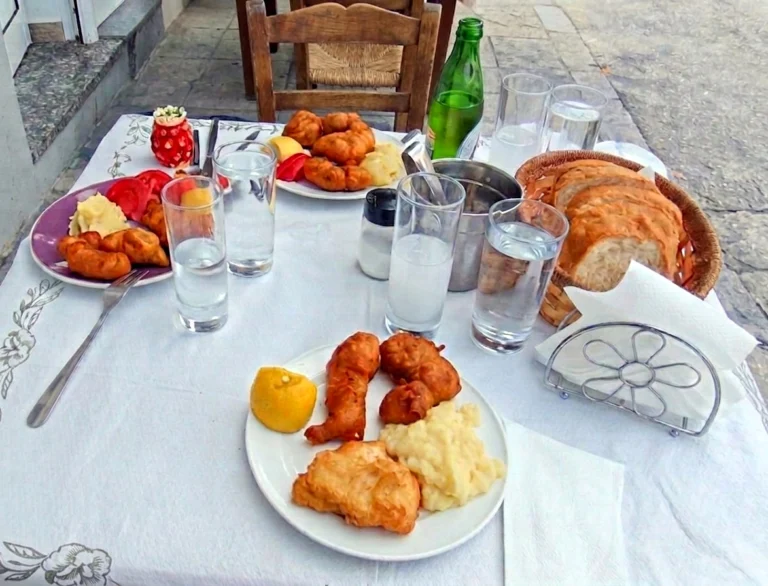 Τραπέζι σε αυλή με ποτήρια τσίπουρο, τηγανητούς μεζέδες, λεμόνι, ψωμί και νερό