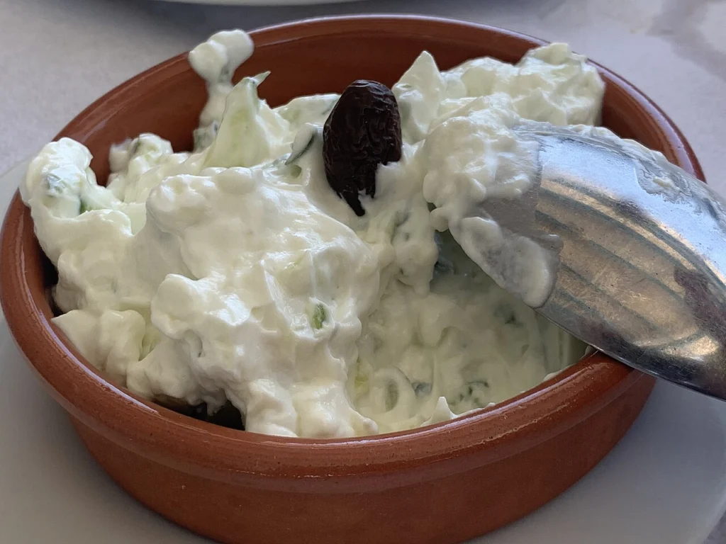 Τζατζίκι σε πήλινο μπολ με αγγούρι και μια ελιά, σερβιρισμένο σε ελληνική ταβέρνα