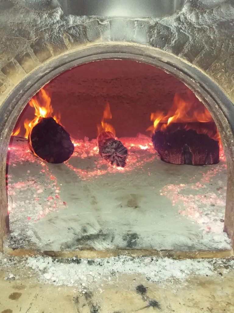 Ξυλόφουρνος με αναμμένα κούτσουρα και κόκκινα κάρβουνα στην Αρτεμισία, κοντά στην Καλαμάτα